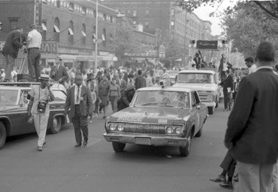  Sam Price in tie walking next to cop car on 138th St.and 7th Ave by the Renaissance Theater